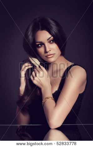 Portrait of beautiful young woman with golden jewelry on black background