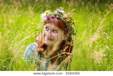 Bela jovem ruiva em uma grinalda de flores
