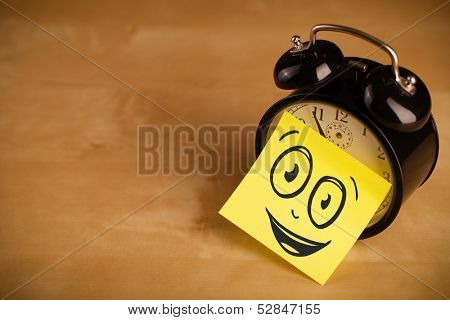 Drawn smiley face on a post-it note sticked on an alarm clock