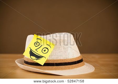 Drawn smiley face on a post-it note sticked on a hat