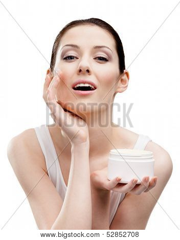 Woman applying cream from container on face, isolated on white. The pursuit of beauty