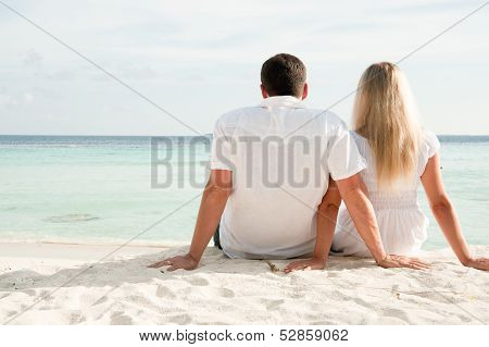 Couple Sittng On Sand Facing Ocean