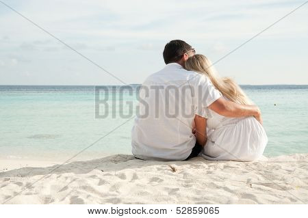 Couple Sittng On Sand Facing Ocean