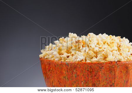 Closeup of a Bowl Full of Popcorn on a light to dark gray background. Horizontal format with copy space.
