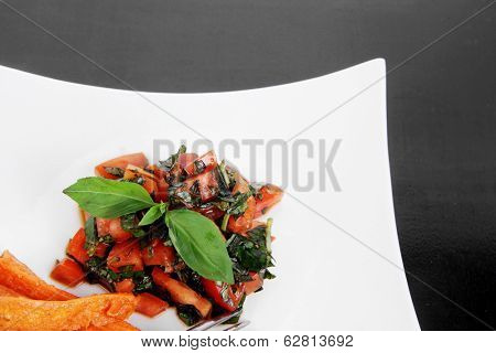 vegetable salad : cherry tomatoes and basil with sweet baked potato served on white plate with sauceboat full blask soy sauce on wood