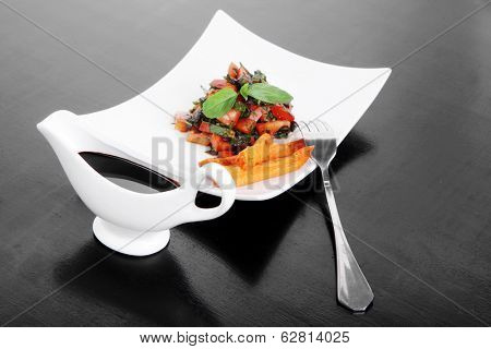 vegetable salad : cherry tomatoes and basil with sweet baked potato served on white plate with sauceboat full blask soy sauce on wood