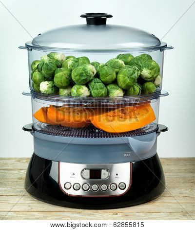 Healthy food in steamer, steam cooker with pumpkin and brussels sprouts