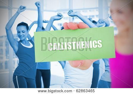 Fit blonde holding card saying callisthenics against class in gym