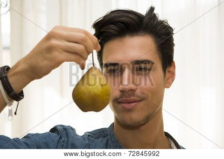 Young Man Holding A Large Ripe Yellow Pear