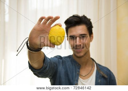Young Man Holding A Large Delicious Ripe Lemon