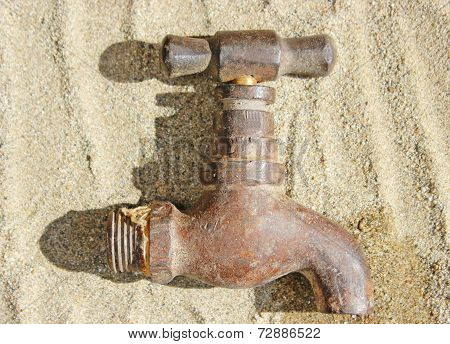 Rustic Water Faucet Tap Lying On Sand