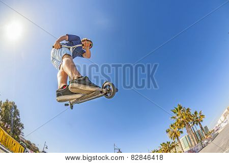 Boy Jumps With His Scooter Over A Ramp