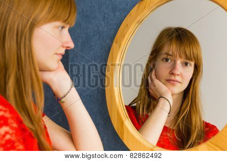 Redhead teenage girl looking in mirror