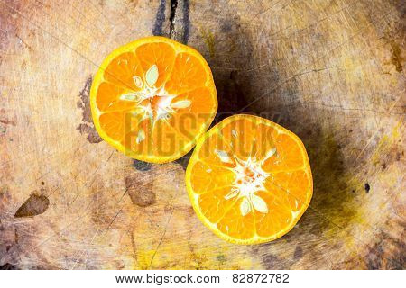Orange cut in half on old chopping board