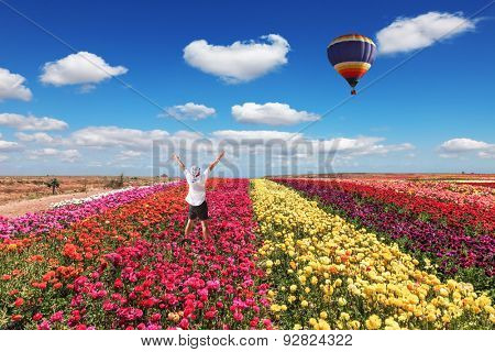 Enthusiastic tourists threw up his hands. Big balloon flies over field of flowering.