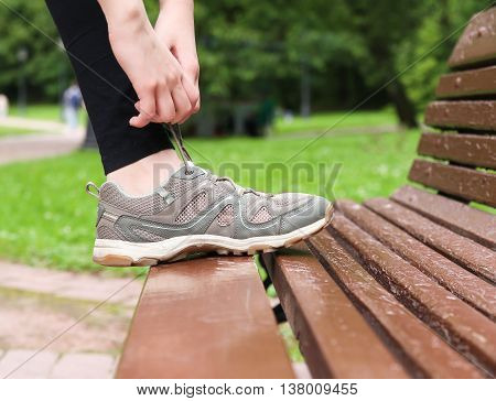 Tying shoelaces on sneakers sports. Macro. Close-up. Bench.