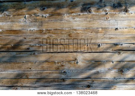 The wooden wall of the house. Cracked boards pattern of light and shadow