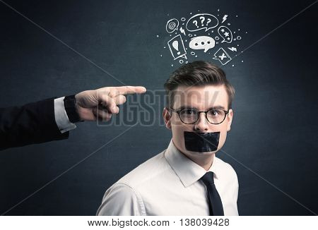 Caucasian business hand pointing at stressed male employee with drawn question, explamation marks, talk bubble above his head