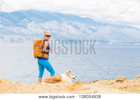 Woman hiking with akita inu dog on seaside trail. Recreation and healthy lifestyle outdoors in summer mountains and sea nature. Beautiful inspirational landscape. Trekking and activity concept.