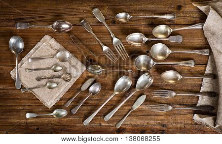Top view of collection of antique kitchen utensils ( spoon fork teaspoon knife tea-strainer) on a old wooden background.