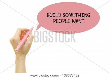 Woman hand writing BUILD SOMETHING PEOPLE WANT with a marker isolated on white.