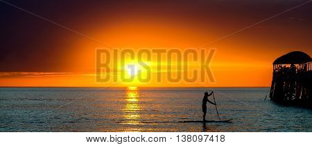 Silhouette of a man paddle surfing at Henely Beach South Australia