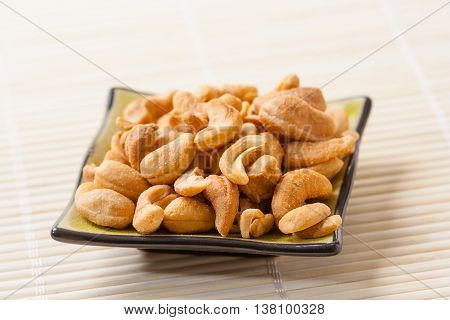 Closeup of a small plate with toasted salted cashew nuts.