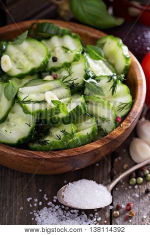 Pickled cucumber with dill and garlick in a rustic wooden bowl