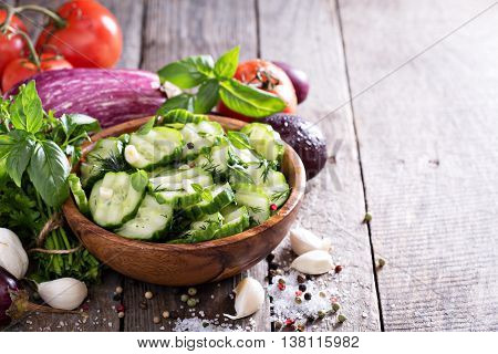 Pickled cucumber with dill and garlick in a rustic wooden bowl