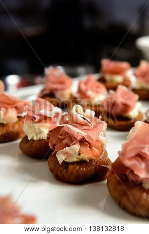 Close up of canapes with slices of prosciutto, tomato and figs