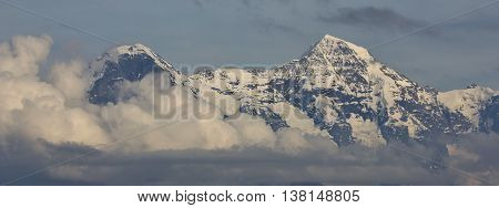 Famous mountains Eiger and Monch surrounded by clouds. Scene in the Swiss Alps.