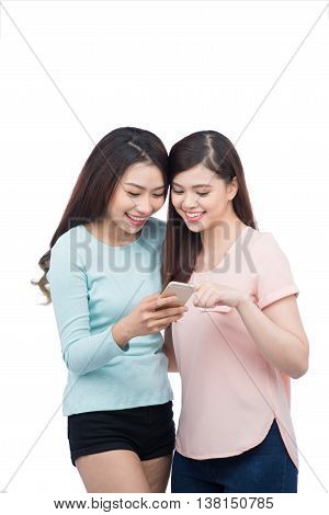 Two young girls using smart phone. Smiling young female friends reading text message