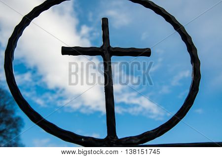 Iron cross in cirkle with sky and clouds in background