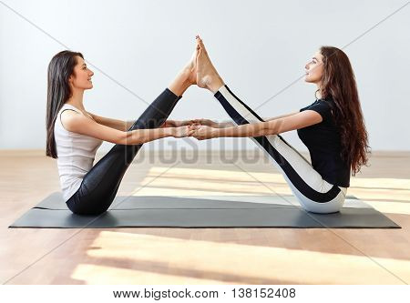 Two Young Women Doing Yoga Asana Buddy Boat Pose
