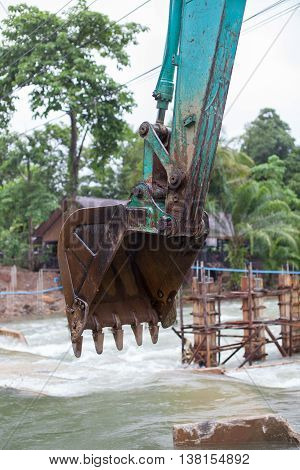 Surat Thane, Thailand-Jun 25 : The excavator machine are use bucket to preparing the land in the Khao-Sok river for building the temporary bridge on Jun 25, 2016 in Surat Thane, Thailand