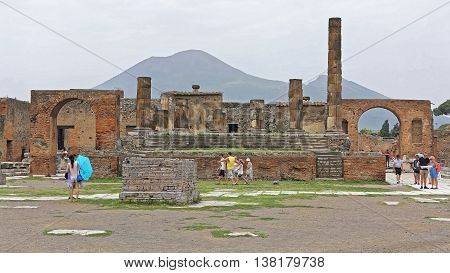 POMPEII ITALY - JUNE 25: The Temple of Jupiter With Tourists in Pompeii on JUNE 25 2014. Ancient Roman Ruins UNESCO World Heritage Site in Pompeii Italy.