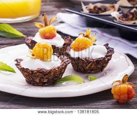 Healthy breakfast. Homemade granola cup with yogurt and fresh cloudberries on a simple wooden background on a ceramic plate. selective focus