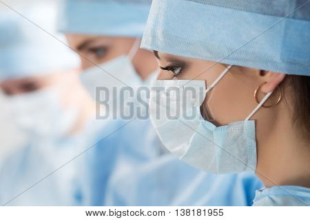 Close-up portrait of young female surgeon doctor surrounded by her team. Group of surgeon in operation theatre. Healthcare medical education emergency medical service and surgery concept