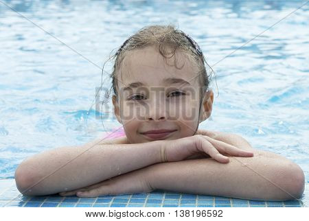portrait of Caucasian brunette young girl of 7 - 8 years old posing in pool with hands crossed