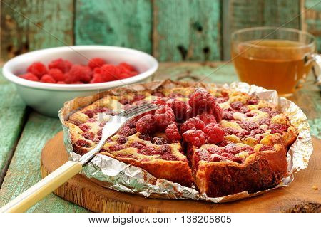 Homemade quark pie with raspberries baked in foil served with green tea closeup