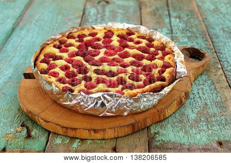 Homemade pie with organic raspberries on wooden board closeup