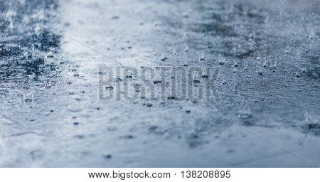 Heavy rain drops on asphalt closeup. Cold rainy weather concept.