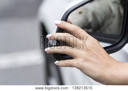 girl adjusts the rearview mirror in a white car