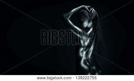 Young fit athletic woman in silver body paint, standing back to camera. Lot of copy space