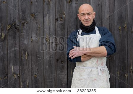Man With Arms Crossed By A Wooden Background