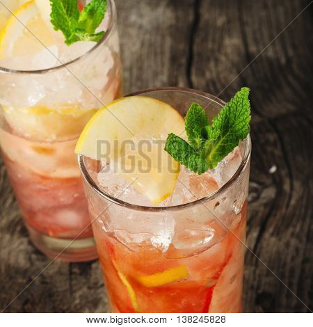 Cranberry cocktail with ice mint lemon and apple closeup. Summer refreshing cocktail