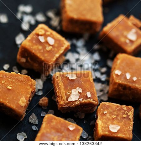 Sweet treats - Salted caramel pieces and sea salt close up. Butter caramel candy macro. Vintage rustic style