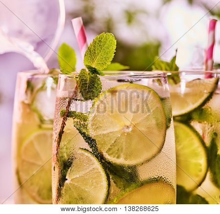 Alcohol drink. On wooden boards top of three glasses with alcohol drink and ice cubes. A drink number hundred thirty nine cocktail mohito with knife and mint leaf. Country life. Light background.