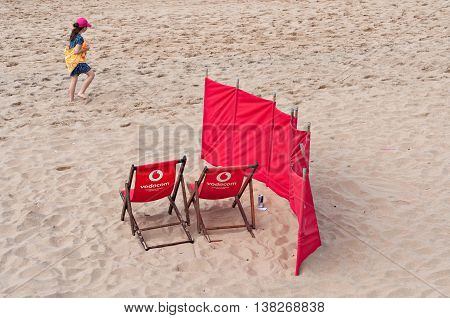DURBAN SOUTH AFRICA - JULY 09 2016: Young girl walks past two Vodacom beach chairs on the beach in Umhlanga Rocks