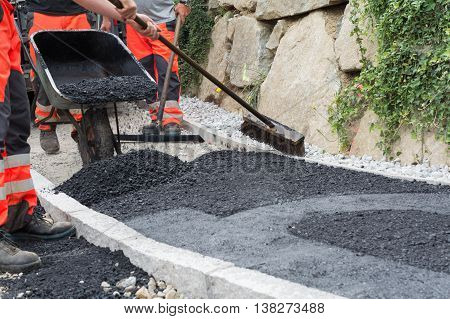 several construction workers with wheelbarrows when pavement asphalting